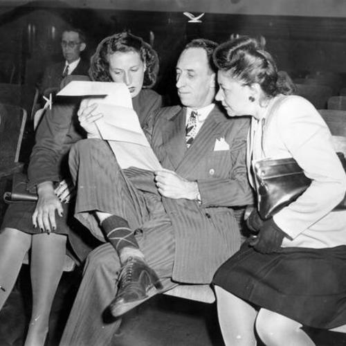 [Harry Bridges in court for his divorce trial, seated with his daughter and Miss Vivian Dolline, a  friend of Miss Bridges]