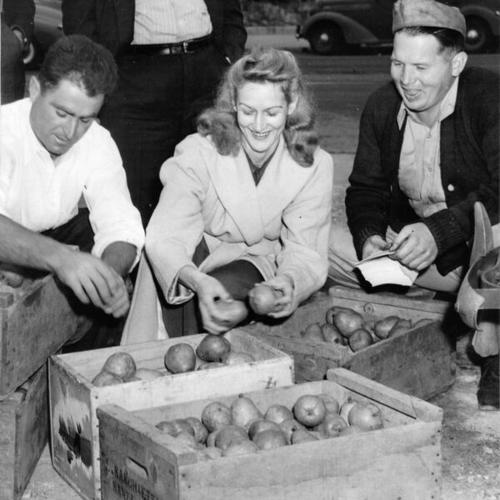 [Mrs. Ralph Riley and Harold Winslow buying pears from Louie Sanchetti at the Farmers' Market at Market and Duboce streets]
