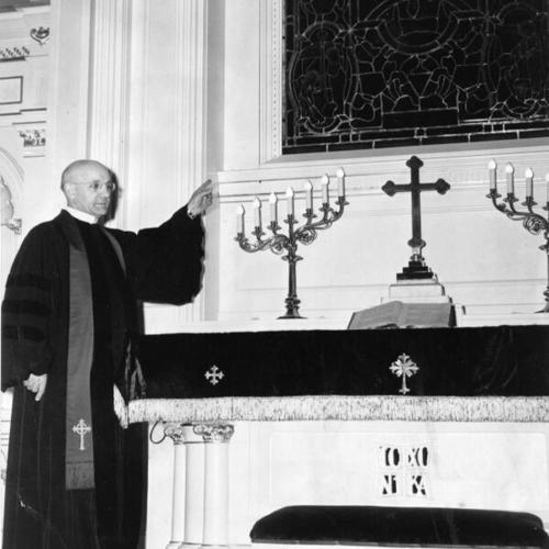 [Rev. J. George Dorn inspecting the stained glass window above the altar of St. Mark's Lutheran Church]