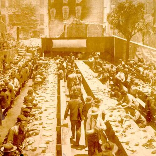 [Workers sitting down for a meal in Union Square, St. Francis Hotel in background]