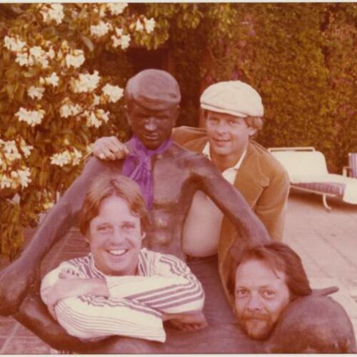 Armistead Maupin (left), Jim Gagner (wearing cap), and Gary with statue in swimming pool area at Rock Hudson's home, The Castle, Beverly Hills