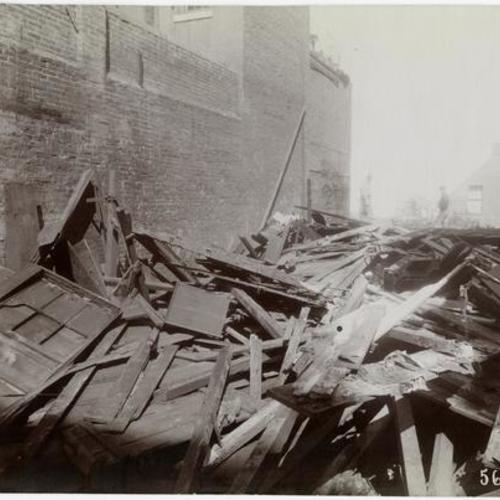 055 People standing in debris of wooden building during demolition