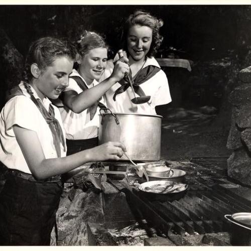 [San Francisco Camp Fire Girls Judy King, Martha Gregory and Joan Dawson preparing a meal during their weekend at Mt. Tamalpais]