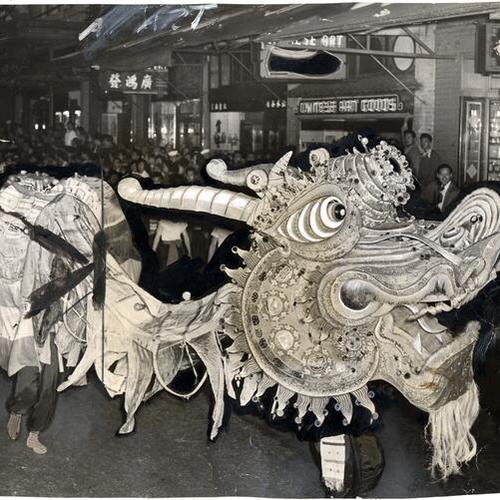 [Dragon dancing down street as part of Chinese New Year parade]