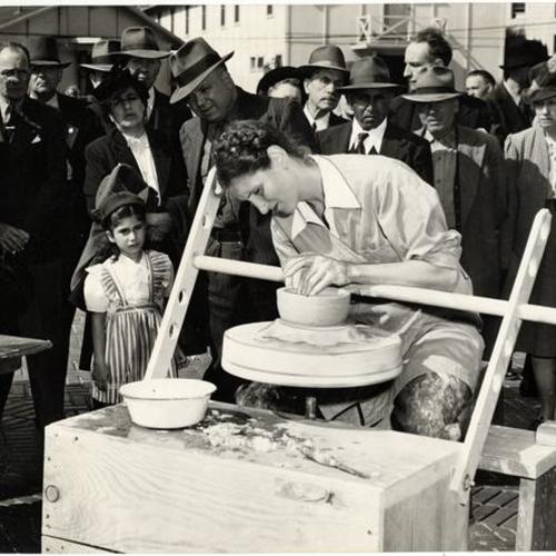 [Jane McVeigh working on a pottery piece at the Civic Center outdoor art show]