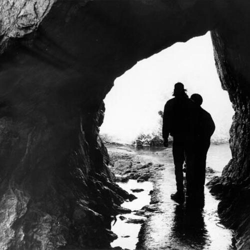 [Two people standing in a cave near Sutro Baths]