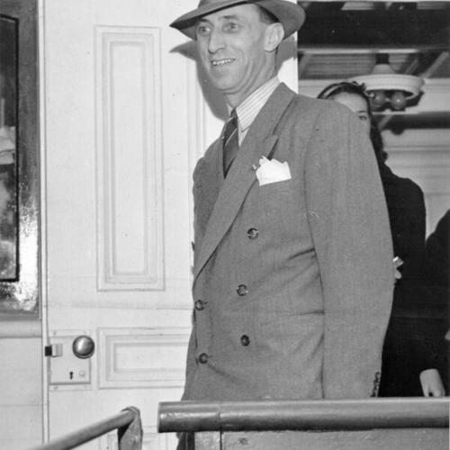 [Harry Bridges smiling as he boards a boat for Angel Island]