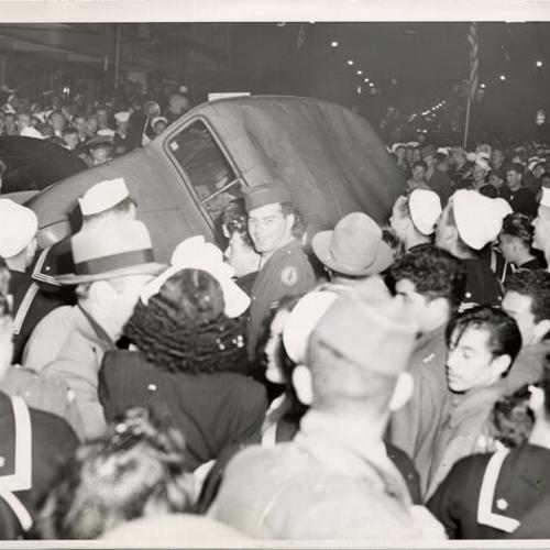 [Crowd of people overturning a newspaper delivery truck during all night celebration of Tokyo surrender report]