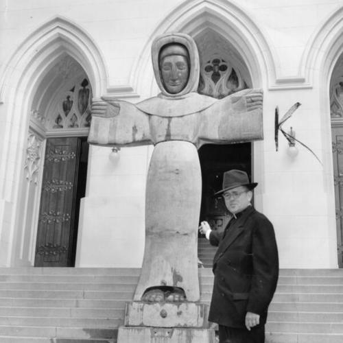 [Father Alvin P. Wagner standing in front of statue of Saint Francis of Assisi at the entrance to the St. Francis of Assisi Church]