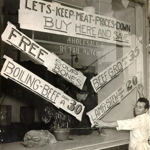 [Louis Ranieri putting up signs advertising low meat prices in the window of the Panelli Meat Company shop at 801 Columbus Avenue]