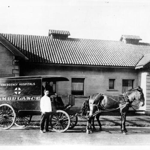[Dr. George K. Herzog (in white coat) standing next to a horse drawn ambulance]