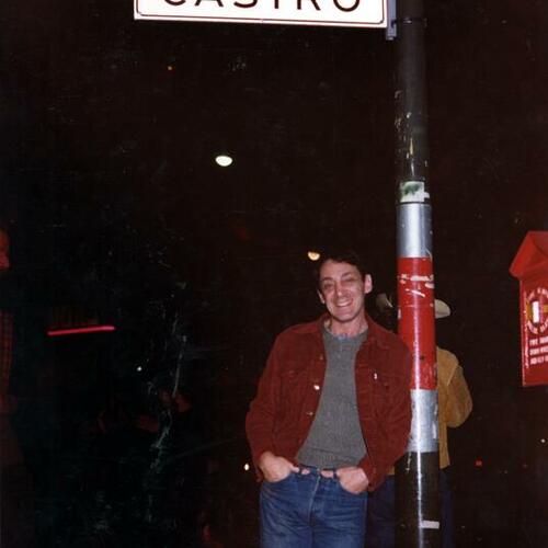 [Harvey Milk leaning against Castro Street sign, New Year's Eve 1977]