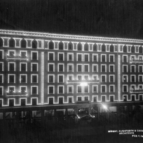 [Exterior of Whitcomb Hotel lit up with white lights]