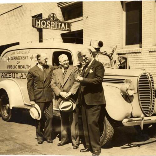 [Dr. Edmund Butler, Chief Surgeon, James O'Dea, Chief Steward, and Dr. J. C. Geiger standing next to a new ambulance in front of Central Emergency Hospital]