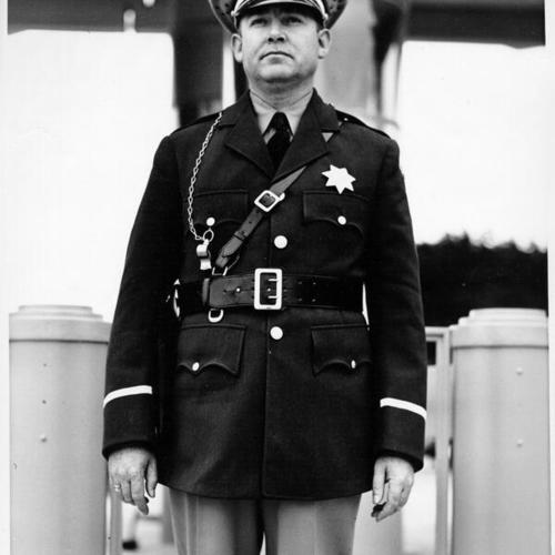 [Captain Logan, toll collector at Golden Gate Bridge, standing in front of toll plaza]