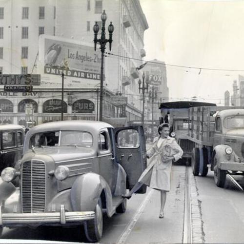 [Woman stepping out of an automobile into traffic on Market Street]