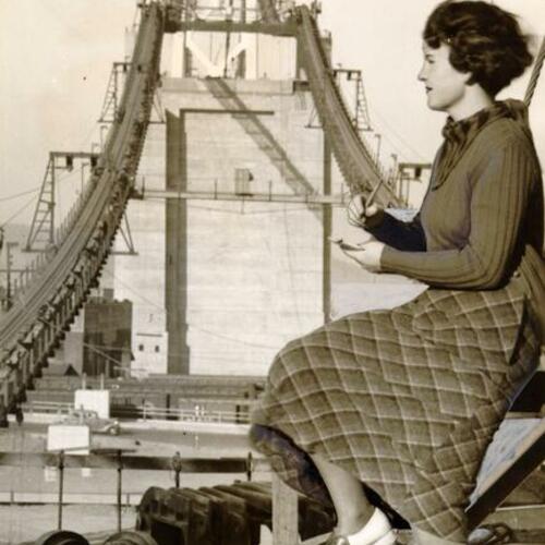 [Barbara Smitten sitting and writing while San Francisco-Oakland Bay Bridge being constructed in background]