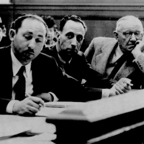 [Richard Gladstein, left, and Harold Sawyer, right, flank Harry Bridges as the three listen to Mrs. Agnes Bridges charge her husband with infidelity]
