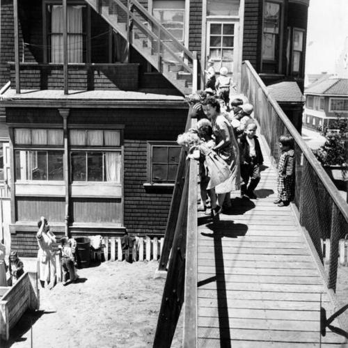 [Mrs. Hugh Miller standing with children on a ramp in the back of the Presidio Hill Nursery School]