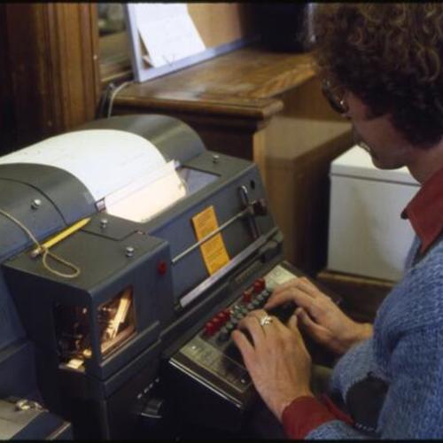 [A man using a teletypewriter]