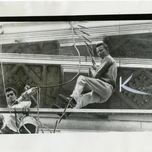 [Leo Moldero and Bill Phelan drilling holes in the granite above the columns on City Hall as part of an effort to keep pigeons off the building]