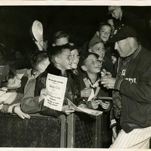 [Lefty O'doul signs autographs for a group of boys]