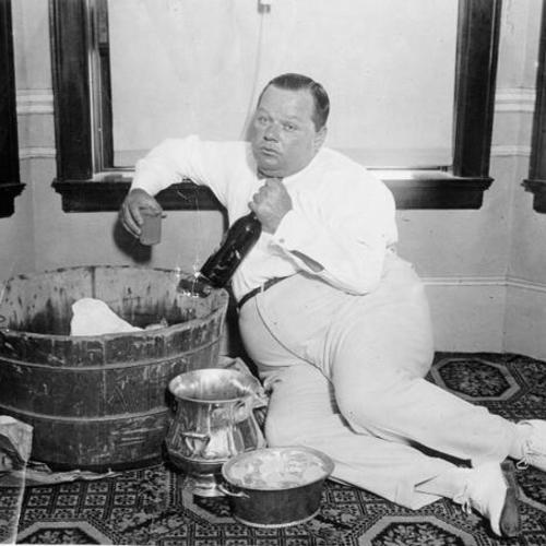 [Roscoe "Fatty" Arbuckle with bottle and glass of champaign]