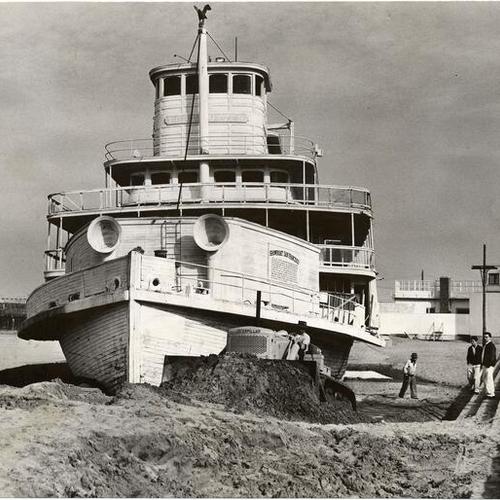 [Dave Devincenzi bulldozing sand around beached riverboat "Fort Sutter" at Aquatic Park]