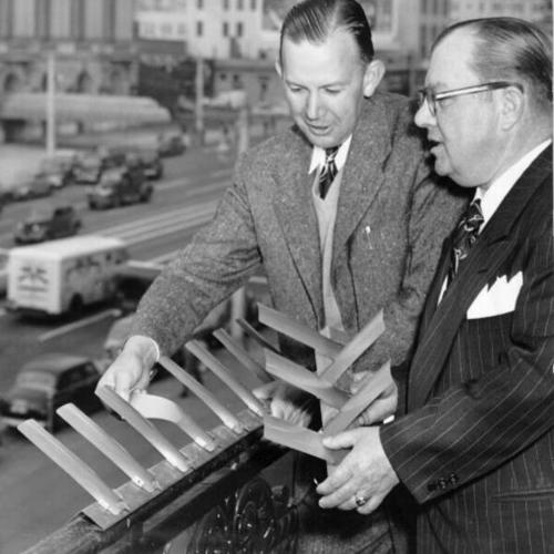 [V. H. Montgomery demonstrating a device designed to keep pigeons off City Hall to Supervisor Dewey Mead]