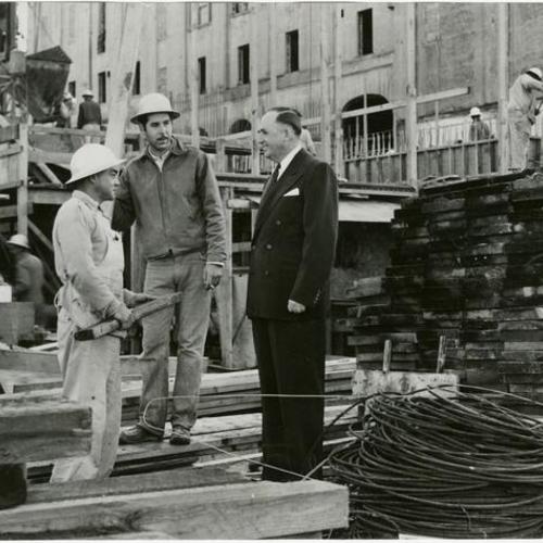 [William C. Figge, president of the Theo. Hamm Brewing Company, talking with two construction workers at the site of the new Hamm's Brewery in San Francisco]