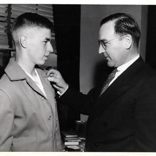 [District Attorney Edmund J. Brown awards a medal for service to Robert Kirk during the National Boys Club Week]