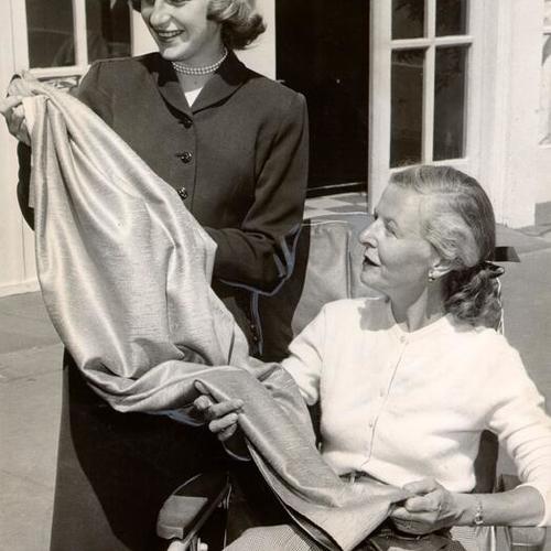 [Miss Sallie Frier and Mrs. Harold J. Franklin inspecting a piece of drapery fabric for possible use in the student nurse quarters at St. Francis Hospital]