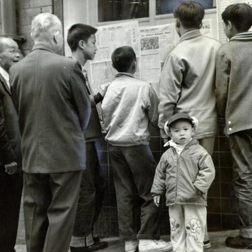 [Group of men reading notices outside The Young China newspaper office in Chinatown]