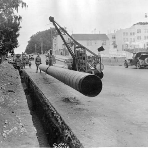 [20 inch pipe being lowered into a trench along the side of Masonic Avenue, near Golden Gate Avenue]