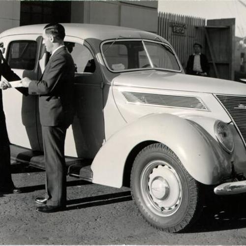 [Babe Maggini, head of Maggini Motor Car Company, delivering a new car to customer Harry Griffith]