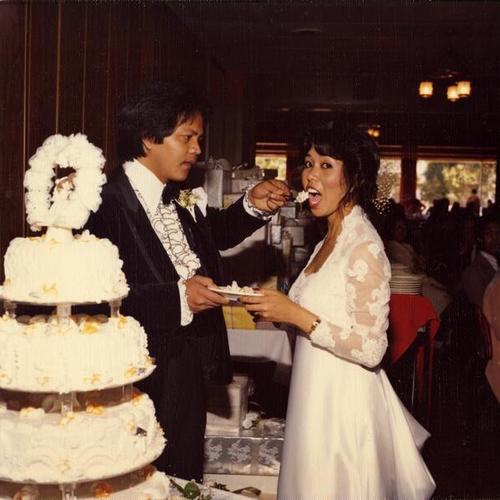 [Bride and groom, Almerita and Emir, cutting the wedding cake and taking first bite]