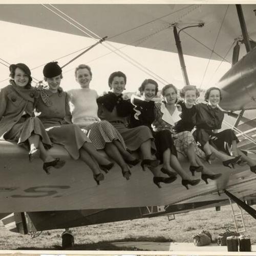 [Group of women posing on an airplane wing at Crissy Field]