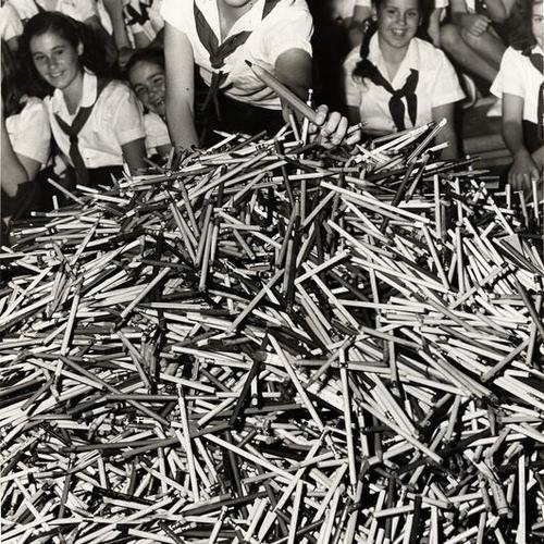 [Camp Fire Girl Ruth Hudgens putting the last pencil atop the pile collected for European school children]