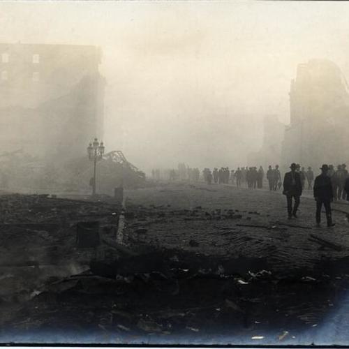 [View, from near Ferry Building, of groups of people walking past ruins on Market Street]