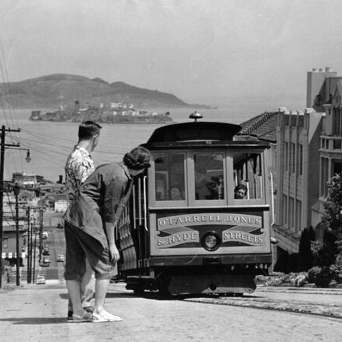 [Dwane Hodgson and Carol Lyle watching a Hyde Street Cable Car]