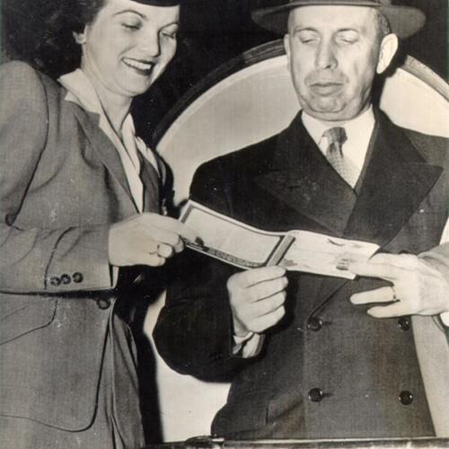 [James V. Bennett, director of the Federal Bureau of Prisons, being greeted by airline hostess Rita Phillips upon his arrival in San Francisco from Washington D. C. to investigate prison break and riot on Alcatraz]
