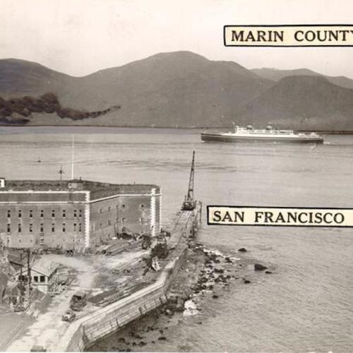 [Early stages of construction of trestle bridge to Golden Gate Bridge south tower anchorage showing Fort Point in foreground and Marin hills in background]