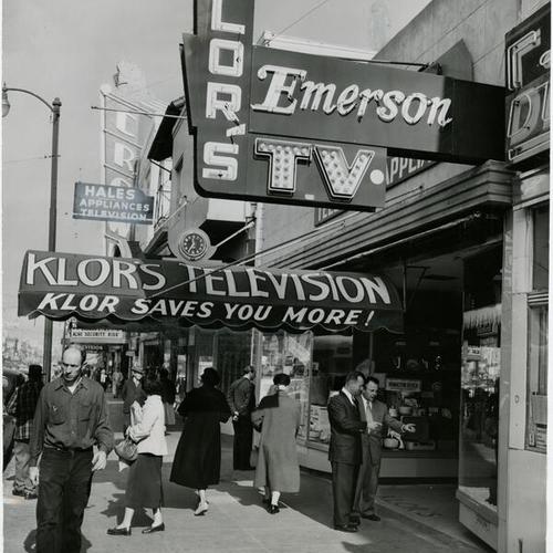 [George Klor and Al Schmidt standing outside Klor's Television and Appliance store at 2581 Mission Street]