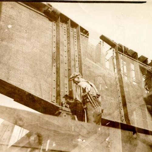 [Worker pounding a pin into a girder during construction of a railway terminal for the San Francisco-Oakland Bay Bridge]