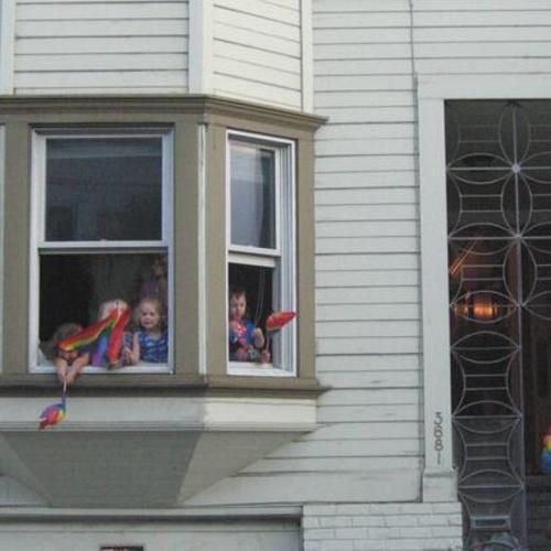 [Children looking out and waving rainbow flags from home during Pink Saturday Dyke March at 18th and Dolores Streets in 2006]