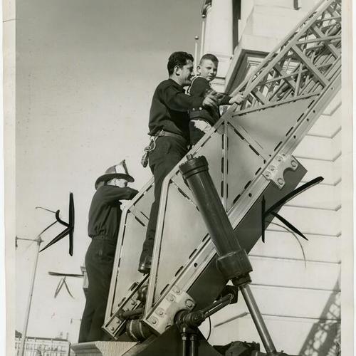 [Firefighter Anthony Bronzovich helps Robert Tillman down on ladder from Civic Auditorium]