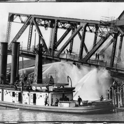 [Fire fighters and fire boat extinguishing fire on Third street bridge]