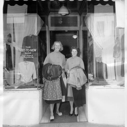 [Mrs. John D. Thomas and Mrs. Gurek Byczkowski standing in the entrance to the Next To New Shop]