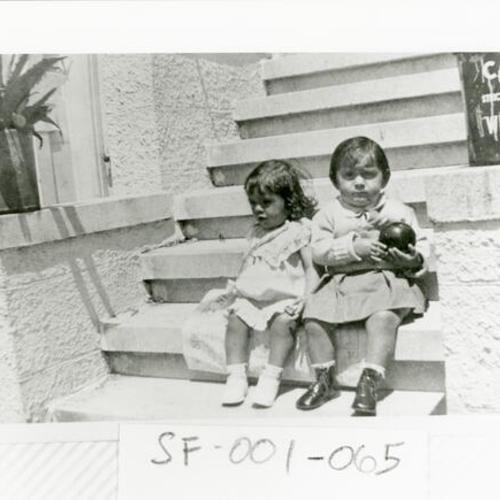 [Two children sitting on steps of a building on Geary Boulevard between Divisadero and Scott Streets in 1935]