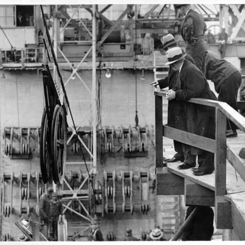 [Men looking at cable spinning work for Golden Gate Bridge]